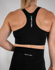 reyllen ladies racerback train top with built in bra black back view worn by woman