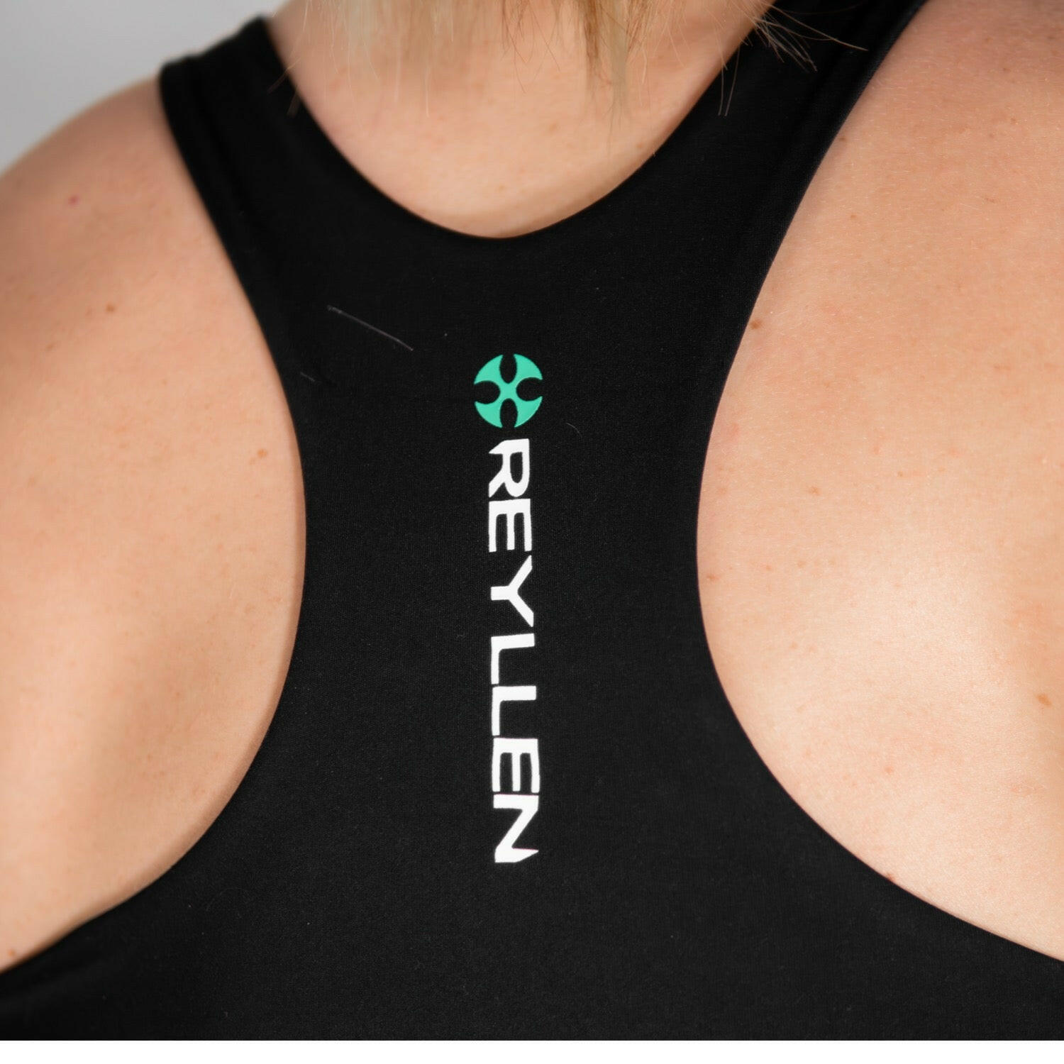 reyllen ladies racerback train top with built in bra black  back logo detail shot