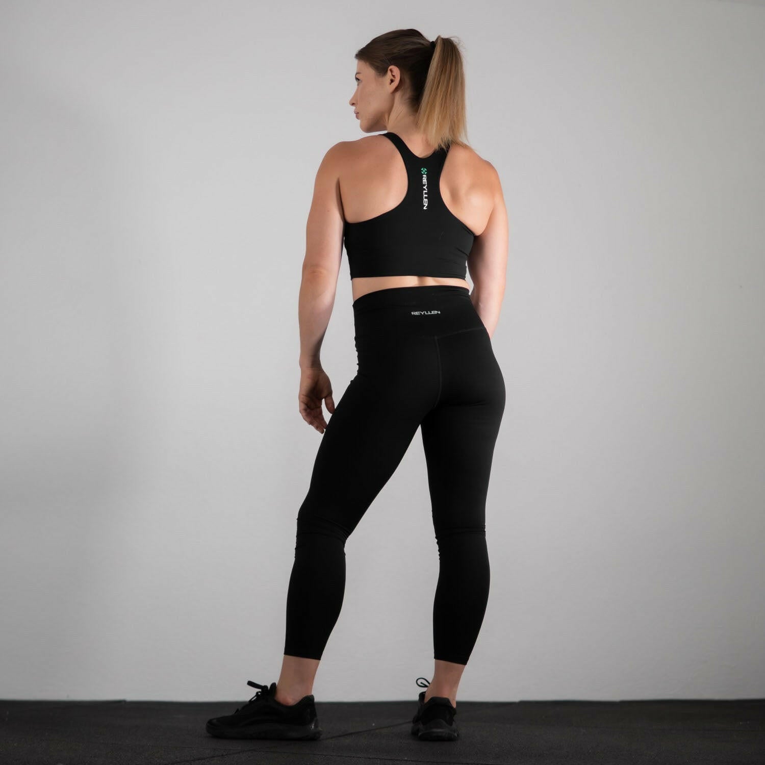 reyllen ladies racerback train top with built in bra black back view worn with leggings