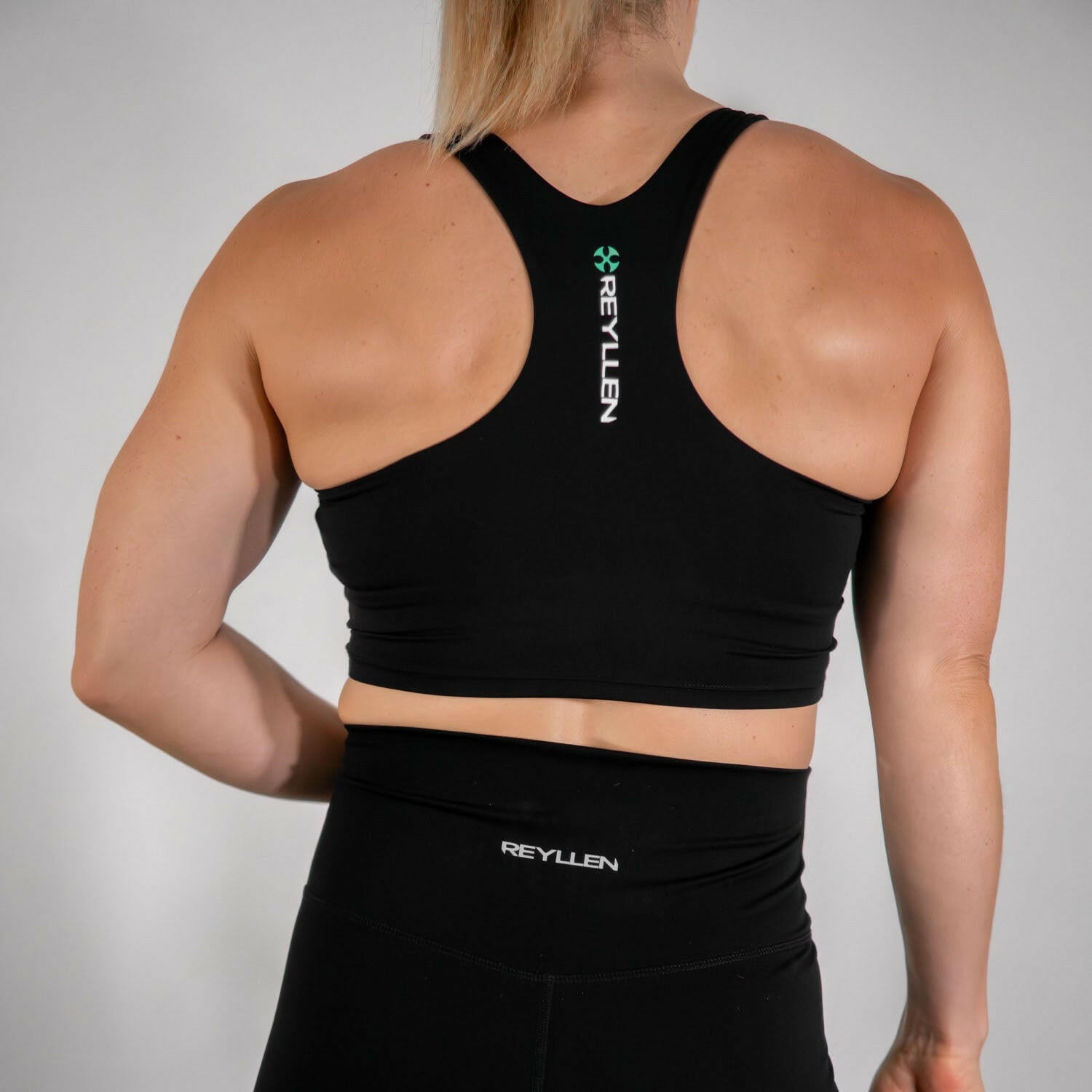 reyllen ladies racerback train top with built in bra black back view worn by woman