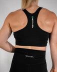 reyllen ladies racerback train top with built in bra black back view worn by woman
